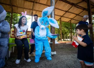 Representantes da Fundação Somar, incluindo um com fantasia de coelho, entregam chocolates a crianças, mostrando onde doar chocolate em Florianópolis durante a campanha de Páscoa.
