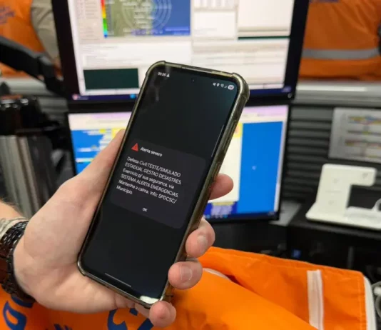Simulado de desastres em Santa Catarina mobiliza estado com alerta de emergência Celular exibe alerta de emergência da Defesa Civil durante simulado de desastres em Santa Catarina, demonstrando o funcionamento do sistema de avisos à população.