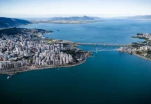 Vista aérea de Florianópolis, com destaque para a área urbana, pontes e o litoral, ilustrando o avanço da cidade em sustentabilidade por meio do programa Florianópolis Lixo Zero.