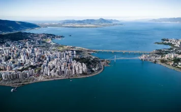 Vista aérea de Florianópolis, com destaque para a área urbana, pontes e o litoral, ilustrando o avanço da cidade em sustentabilidade por meio do programa Florianópolis Lixo Zero.