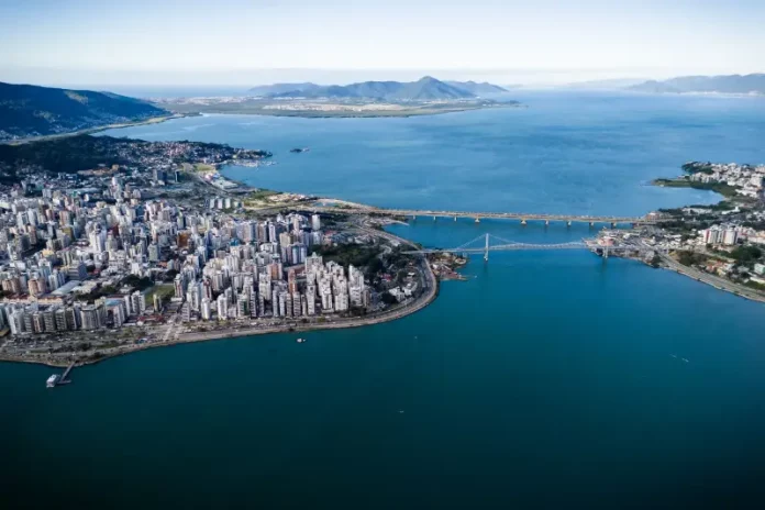 florianopolis-lixo-zero Vista aérea de Florianópolis, com destaque para a área urbana, pontes e o litoral, ilustrando o avanço da cidade em sustentabilidade por meio do programa Florianópolis Lixo Zero.