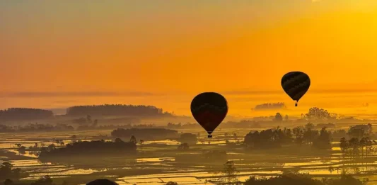 Onda de calor em Santa Catarina mantém temperaturas acima de 32°C no fim de semana Balões coloridos sobrevoando a paisagem sob céu limpo e ensolarado, ilustrando o calor intenso e a onda de calor em Santa Catarina.