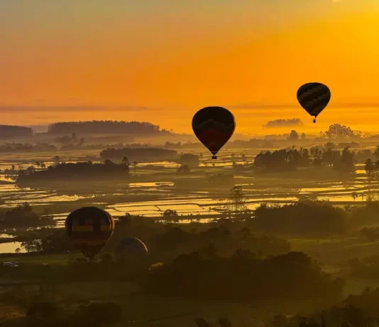 Onda de calor em Santa Catarina mantém temperaturas acima de 32°C no fim de semana Balões coloridos sobrevoando a paisagem sob céu limpo e ensolarado, ilustrando o calor intenso e a onda de calor em Santa Catarina.