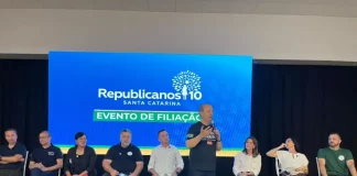 Evento de filiação do Republicanos SC em Palhoça, com o governador Jorginho Mello discursando ao microfone diante de lideranças políticas no palco.