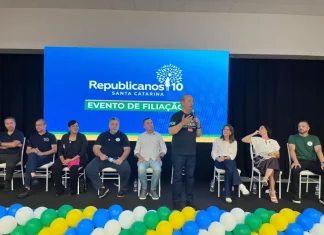 Evento de filiação do Republicanos SC em Palhoça, com o governador Jorginho Mello discursando ao microfone diante de lideranças políticas no palco.