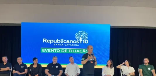 Evento de filiação do Republicanos SC em Palhoça, com o governador Jorginho Mello discursando ao microfone diante de lideranças políticas no palco.
