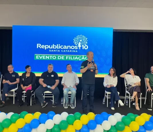 Evento de filiação do Republicanos SC em Palhoça, com o governador Jorginho Mello discursando ao microfone diante de lideranças políticas no palco.