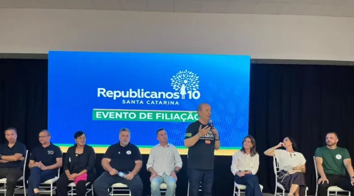 Republicanos SC realiza evento de filiação com mais de 500 pessoas em Palhoça Evento de filiação do Republicanos SC em Palhoça, com o governador Jorginho Mello discursando ao microfone diante de lideranças políticas no palco.