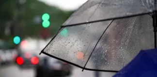 Guarda-chuva com gotas de chuva em rua urbana representa a chegada de temporais em Santa Catarina e a mudança no tempo no início da semana