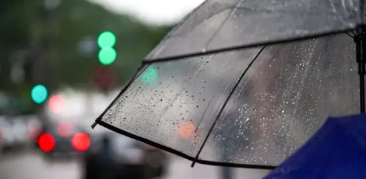 Guarda-chuva com gotas de chuva em rua urbana representa a chegada de temporais em Santa Catarina e a mudança no tempo no início da semana