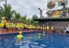 Crianças participam de atividade do Projeto Golfinho SC em piscina, acompanhadas por instrutores, aprendendo práticas de prevenção de afogamentos e segurança na água.