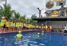 Crianças participam de atividade do Projeto Golfinho SC em piscina, acompanhadas por instrutores, aprendendo práticas de prevenção de afogamentos e segurança na água.