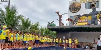 Crianças participam de atividade do Projeto Golfinho SC em piscina, acompanhadas por instrutores, aprendendo práticas de prevenção de afogamentos e segurança na água.