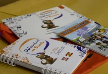 Cadernos e materiais do Programa Defesa Civil na Escola sobre mesa, utilizados para ensinar alunos sobre prevenção de desastres e segurança nas escolas.