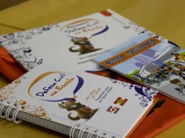 Programa Defesa Civil na Escola alcança 87 mil alunos em SC Cadernos e materiais do Programa Defesa Civil na Escola sobre mesa, utilizados para ensinar alunos sobre prevenção de desastres e segurança nas escolas.
