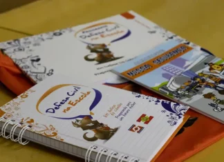 Programa Defesa Civil na Escola alcança 87 mil alunos em SC Cadernos e materiais do Programa Defesa Civil na Escola sobre mesa, utilizados para ensinar alunos sobre prevenção de desastres e segurança nas escolas.