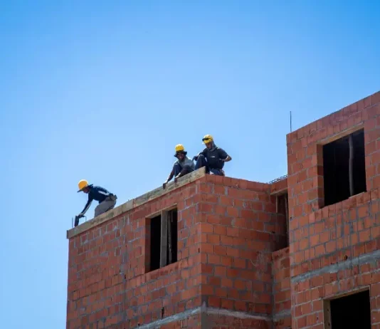 Trabalhadores atuam na construção de unidades habitacionais em Florianópolis, ilustrando o avanço de obras do programa Floripa Para Todos.