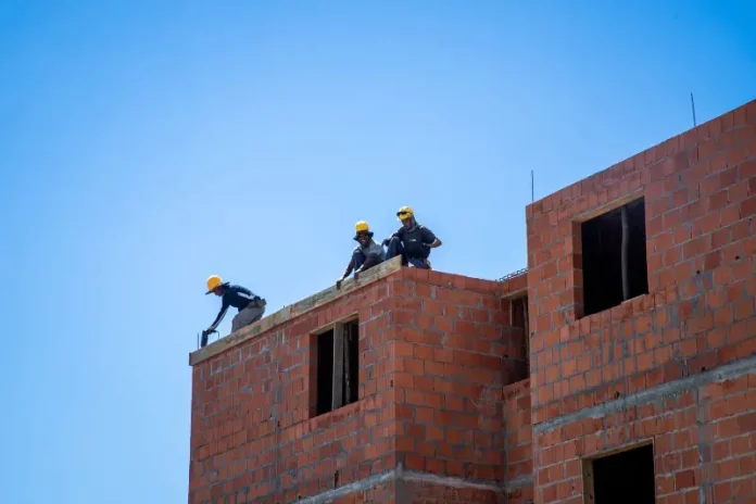 Trabalhadores atuam na construção de unidades habitacionais em Florianópolis, ilustrando o avanço de obras do programa Floripa Para Todos.