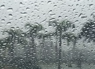 Gotas de chuva intensa sobre vidro com paisagem desfocada ao fundo, ilustrando o tempo instável e o volume elevado de precipitação em Santa Catarina.