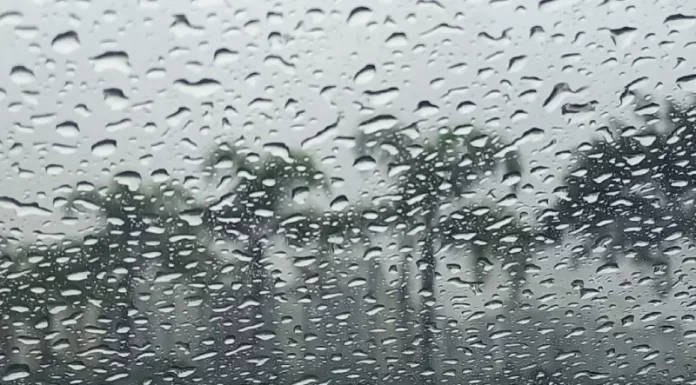 Gotas de chuva intensa sobre vidro com paisagem desfocada ao fundo, ilustrando o tempo instável e o volume elevado de precipitação em Santa Catarina.