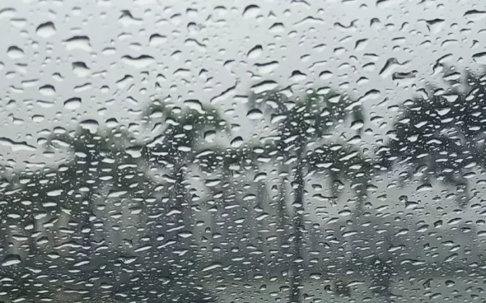 Gotas de chuva intensa sobre vidro com paisagem desfocada ao fundo, ilustrando o tempo instável e o volume elevado de precipitação em Santa Catarina.