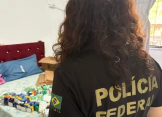 PF e Anvisa combatem comércio ilegal de medicamentos para emagrecimento Policial federal durante ação contra comércio ilegal de medicamentos, com remédios apreendidos sobre cama em residência.