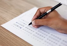 Mão preenchendo gabarito de prova, simulando participação no concurso da InvestSC.