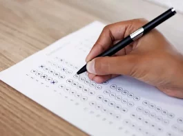 Mão preenchendo gabarito de prova, simulando participação no concurso da InvestSC.