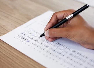 Mão preenchendo gabarito de prova, simulando participação no concurso da InvestSC.