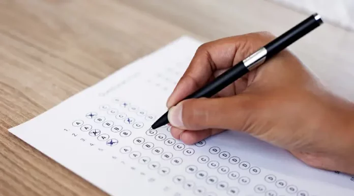 Mão preenchendo gabarito de prova, simulando participação no concurso da InvestSC.