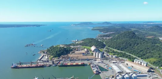 Vista aérea de complexo portuário em Santa Catarina, com navios atracados, armazéns e área de carga e descarga, ilustrando a atividade da Economia do Mar e sua importância para a logística e geração de empregos no estado.
