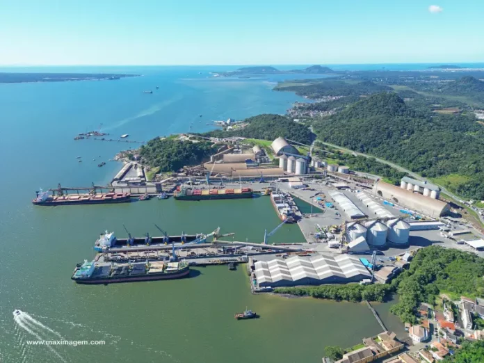 Vista aérea de complexo portuário em Santa Catarina, com navios atracados, armazéns e área de carga e descarga, ilustrando a atividade da Economia do Mar e sua importância para a logística e geração de empregos no estado.