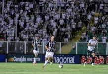 Torcedores do Figueirense acompanham a partida entre Figueirense e Botafogo-SP, no estádio Orlando Scarpelli, enquanto jogadores disputam a bola em campo, ilustrando o clima do jogo e a presença da torcida no futebol catarinense.
