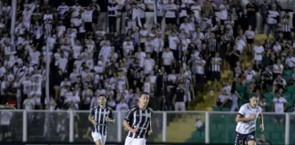 Torcedores do Figueirense acompanham a partida entre Figueirense e Botafogo-SP, no estádio Orlando Scarpelli, enquanto jogadores disputam a bola em campo, ilustrando o clima do jogo e a presença da torcida no futebol catarinense.