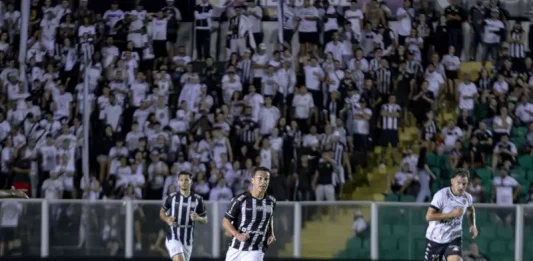 Torcedores do Figueirense acompanham a partida entre Figueirense e Botafogo-SP, no estádio Orlando Scarpelli, enquanto jogadores disputam a bola em campo, ilustrando o clima do jogo e a presença da torcida no futebol catarinense.