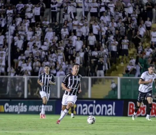 Torcedores do Figueirense acompanham a partida entre Figueirense e Botafogo-SP, no estádio Orlando Scarpelli, enquanto jogadores disputam a bola em campo, ilustrando o clima do jogo e a presença da torcida no futebol catarinense.