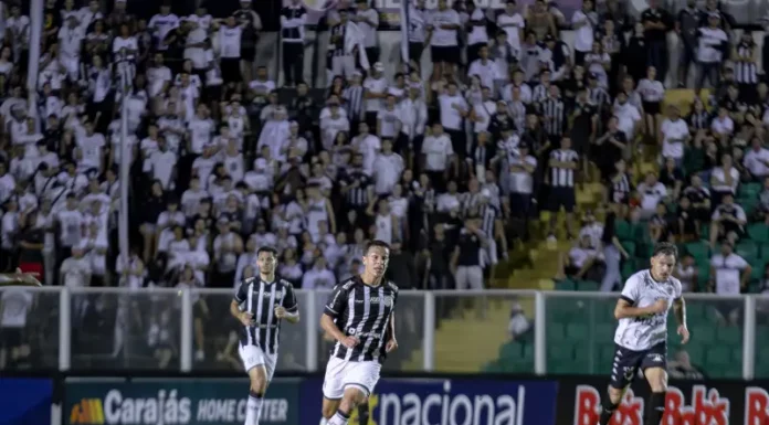 Torcedores do Figueirense acompanham a partida entre Figueirense e Botafogo-SP, no estádio Orlando Scarpelli, enquanto jogadores disputam a bola em campo, ilustrando o clima do jogo e a presença da torcida no futebol catarinense.