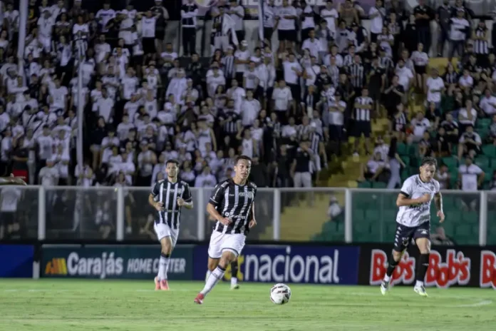 Torcedores do Figueirense acompanham a partida entre Figueirense e Botafogo-SP, no estádio Orlando Scarpelli, enquanto jogadores disputam a bola em campo, ilustrando o clima do jogo e a presença da torcida no futebol catarinense.