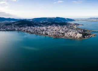 Vista aérea de Florianópolis, mostrando a área urbana cercada pelo mar, utilizada para ilustrar a cidade que aderiu à Declaração de Belém e adotou medidas de compras públicas sustentáveis.