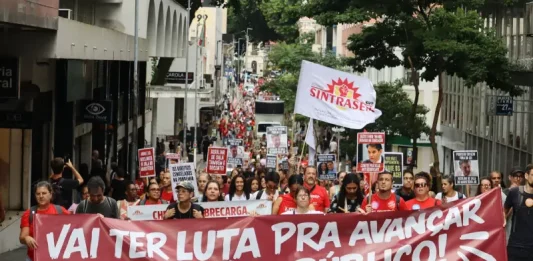 Servidores públicos participam de manifestação durante a greve servidores Florianópolis, com faixa do Sintrasem e cartazes com reivindicações da categoria em rua central.