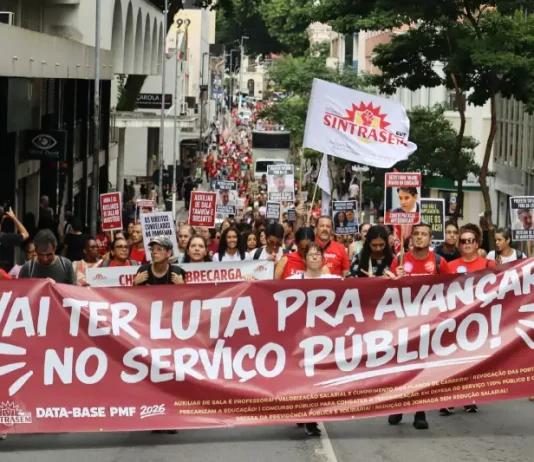 Servidores públicos participam de manifestação durante a greve servidores Florianópolis, com faixa do Sintrasem e cartazes com reivindicações da categoria em rua central.
