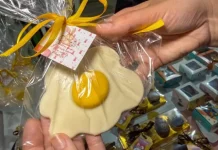 Pessoa segura um doce artesanal em formato de ovo frito, embalado para presente, representando produtos criativos de pequenos negócios para a Páscoa.