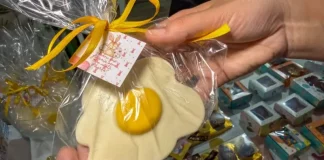 Pessoa segura um doce artesanal em formato de ovo frito, embalado para presente, representando produtos criativos de pequenos negócios para a Páscoa.