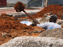Trabalhador realiza escavação em via urbana para implantação do Plano Diretor de Drenagem Urbana em São José, ilustrando ações de infraestrutura para prevenção de alagamentos e melhoria do escoamento da água.