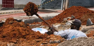 Trabalhador realiza escavação em via urbana para implantação do Plano Diretor de Drenagem Urbana em São José, ilustrando ações de infraestrutura para prevenção de alagamentos e melhoria do escoamento da água.