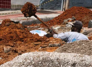 Trabalhador realiza escavação em via urbana para implantação do Plano Diretor de Drenagem Urbana em São José, ilustrando ações de infraestrutura para prevenção de alagamentos e melhoria do escoamento da água.
