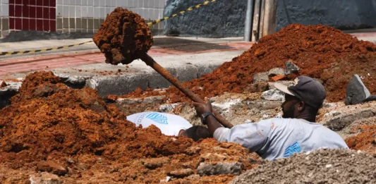 Trabalhador realiza escavação em via urbana para implantação do Plano Diretor de Drenagem Urbana em São José, ilustrando ações de infraestrutura para prevenção de alagamentos e melhoria do escoamento da água.