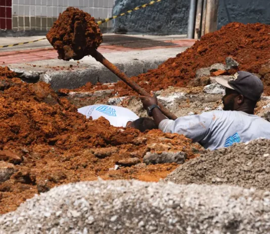 Trabalhador realiza escavação em via urbana para implantação do Plano Diretor de Drenagem Urbana em São José, ilustrando ações de infraestrutura para prevenção de alagamentos e melhoria do escoamento da água.