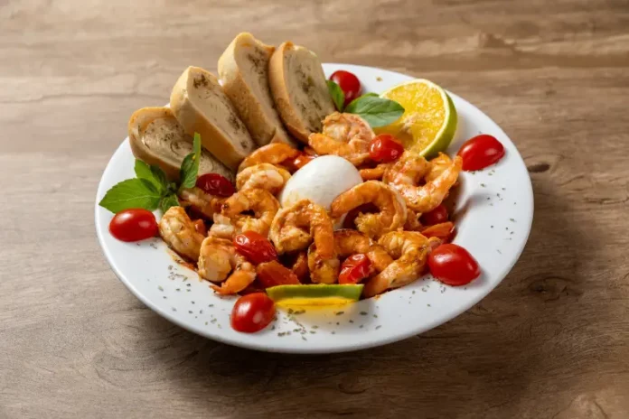 Prato do Festival Brasil Sabor com camarões salteados, burrata, tomates-cereja, pão e fatias de limão, destacando a gastronomia catarinense.