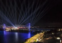 Centenário da Ponte Hercílio Luz reúne cerca de 100 mil pessoas no fim de semana Vista aérea mostra o público reunido na Beira-Mar Continental durante as comemorações do centenário da Ponte Hercílio Luz, em Florianópolis, com palco de shows, iluminação especial e feixes de luz sobre a ponte durante evento noturno.